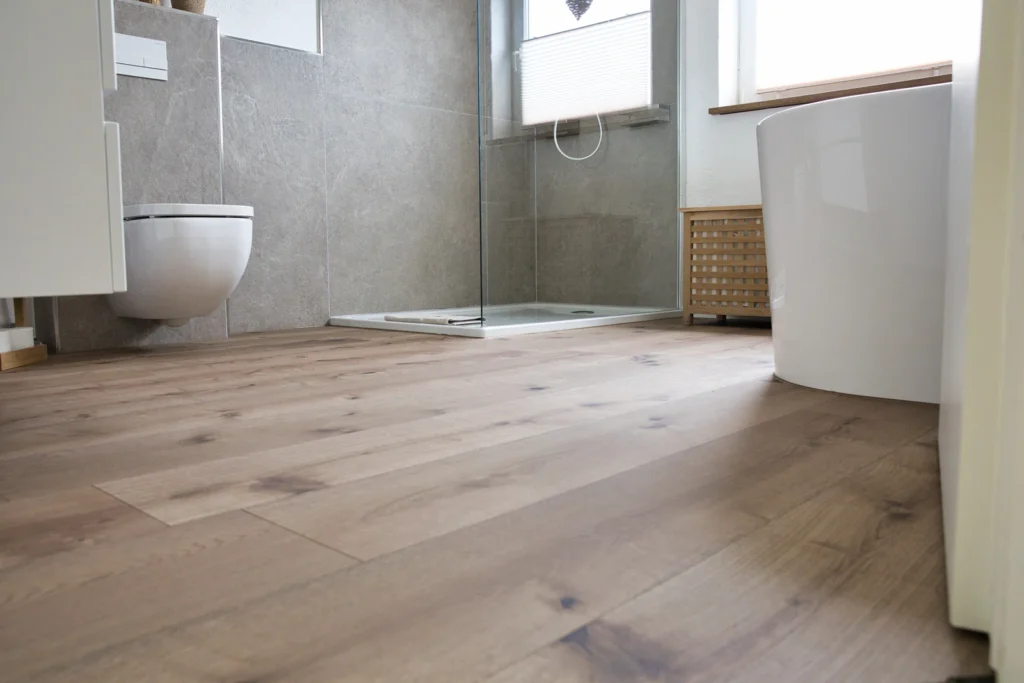 Modernes Badezimmer mit Holzfußboden, Dusche, WC und Badewanne