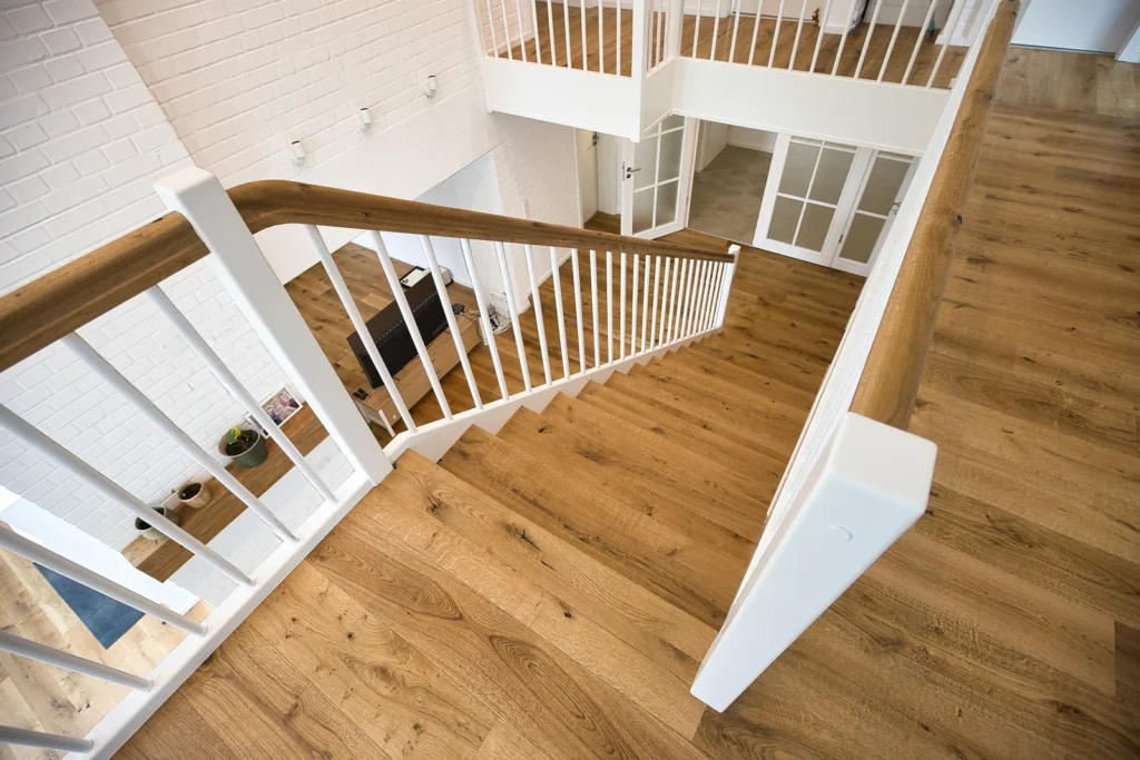 Treppe mit Holzstufen und weißem Geländer in Galeriegeschoss mit Parkettboden