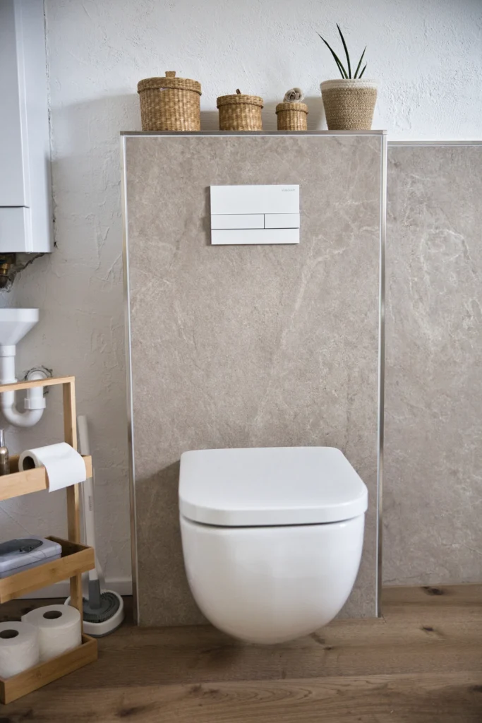Wandhängendes WC vor Natursteinfliesen mit Holzdeko