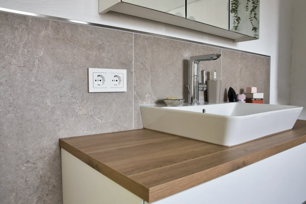 Modernes Waschbecken mit Holzplatte und Spiegelschrank