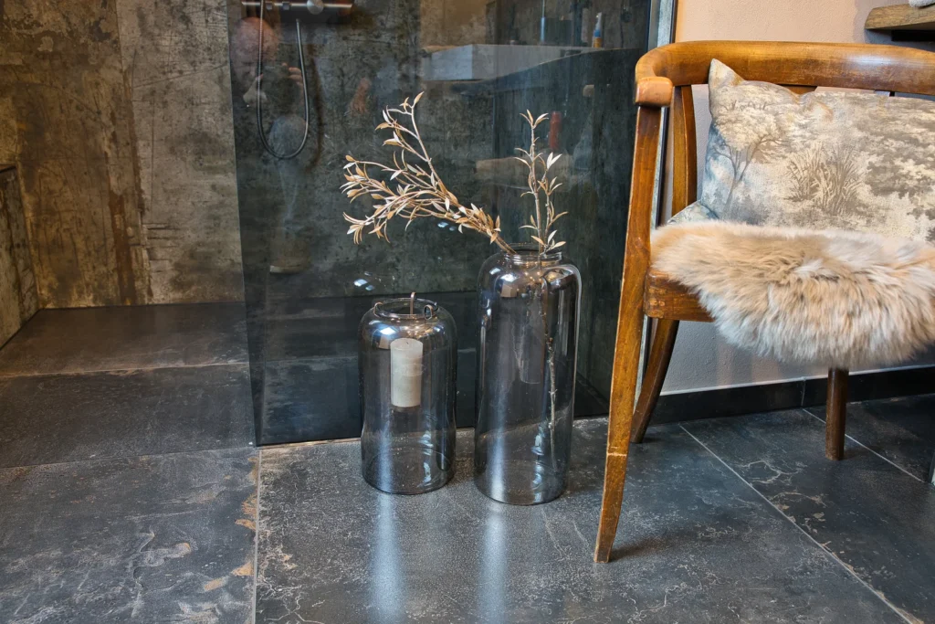 Dekorative Glasvasen und Holzstuhl mit Fellauflage vor Dusche mit Glasabtrennung – Bad Queidersbach