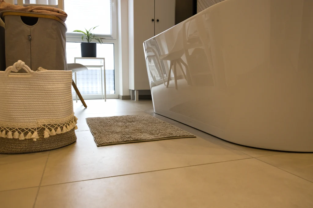 Heller Badezimmerboden mit Accessoires und Blick auf freistehende Badewanne – Vatter Badstudio