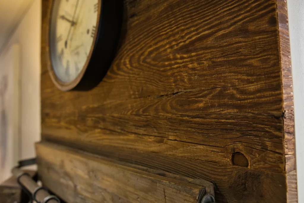 Detailansicht einer rustikalen Wandverkleidung aus Altholz mit nostalgischer Wanduhr in Queidersbach