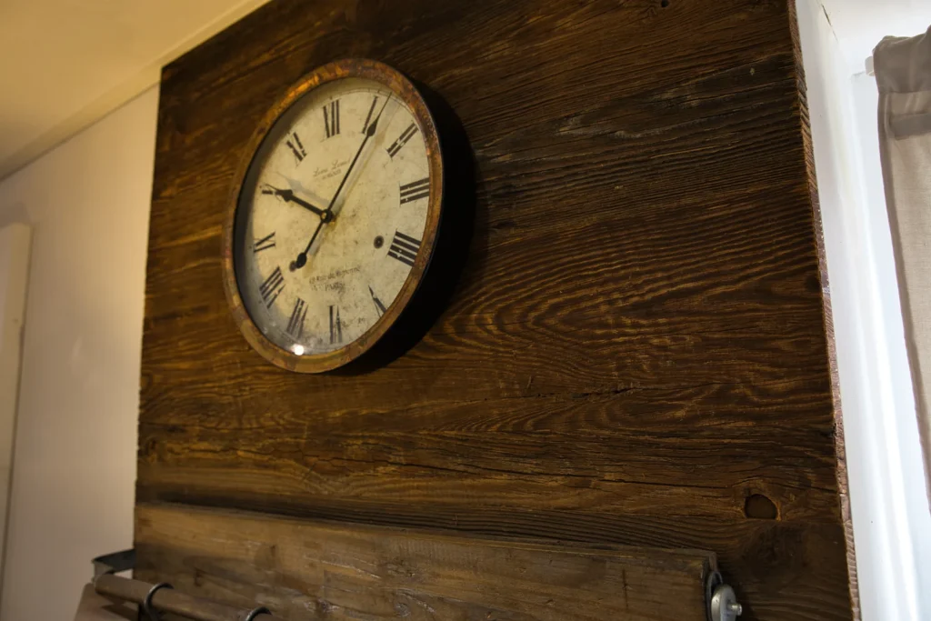 Nostalgische Wanduhr auf dekorativer Altholzverkleidung in einem Wohnbereich in Queidersbach