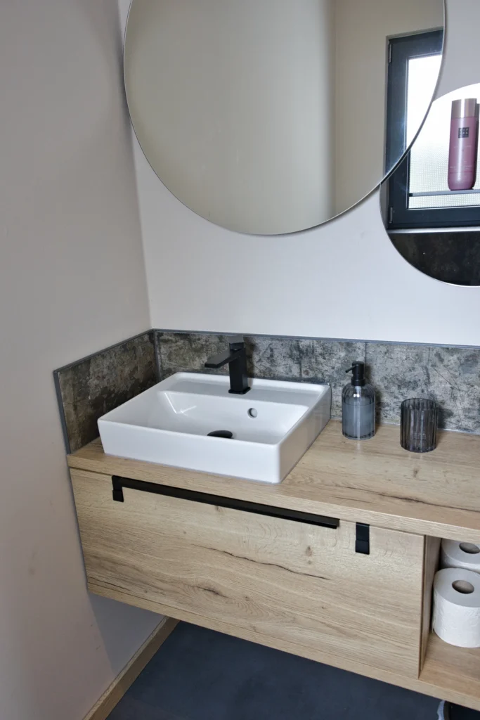 Waschplatz mit Aufsatzwaschbecken, Holzfront und schwarzer Armatur im Gäste-WC
