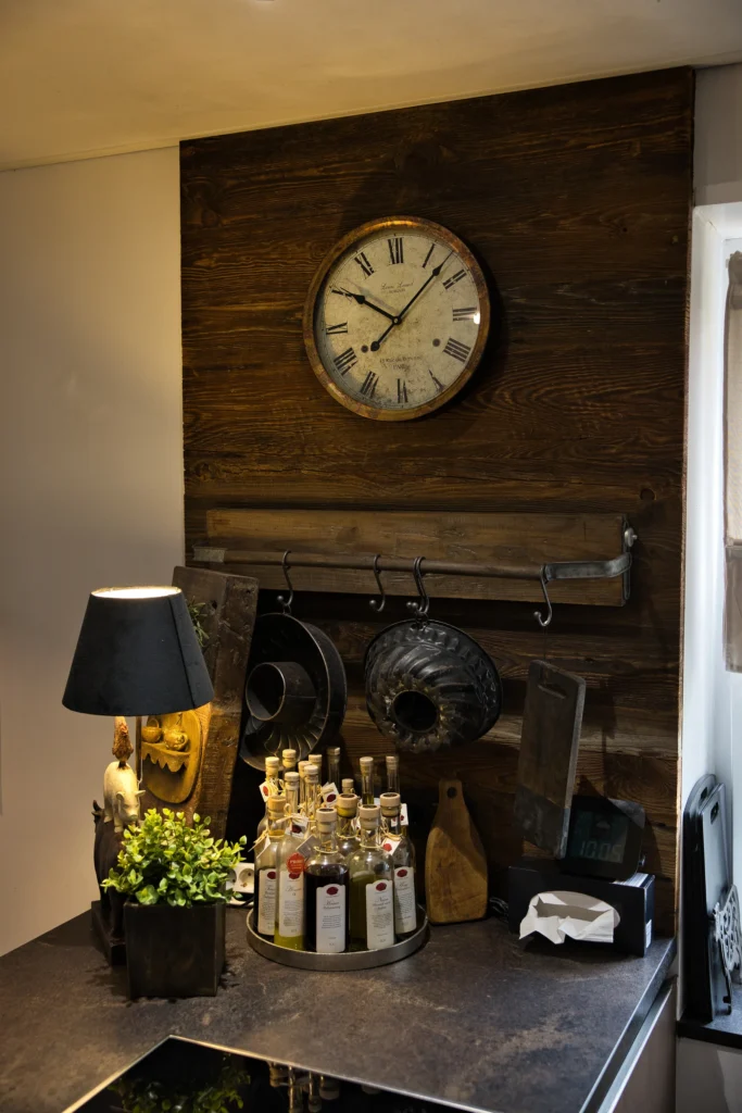 Küchenbereich mit Wandverkleidung aus Altholz, nostalgischer Uhr und dekorativen Küchenaccessoires