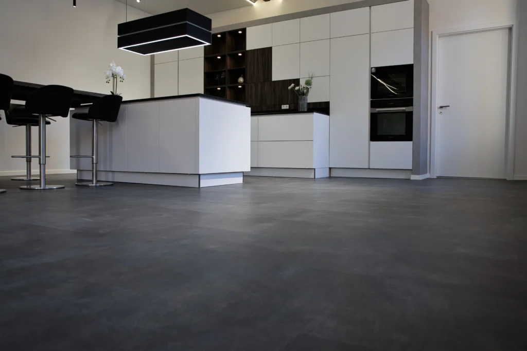 Moderne Einbauküche mit Kochinsel, weißen Fronten und dunklem Vinylboden
