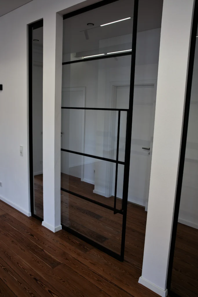 Moderne Glas-Schiebetür mit schwarzem Rahmen von Piktura auf Holzboden