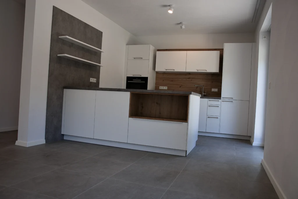 Moderne Einbauküche mit weißen Fronten, Holzrückwand und grauen Fliesen