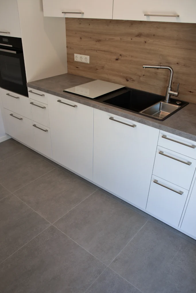 Moderne Einbauküche mit Holzrückwand und grauen Bodenfliesen