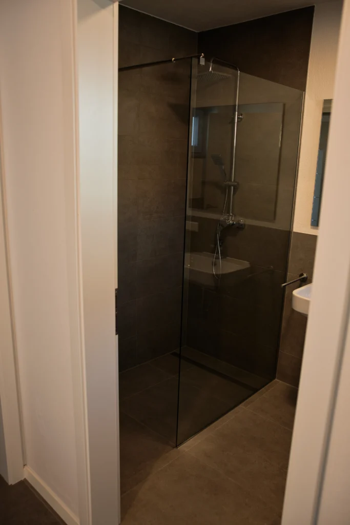 Begehbare Dusche mit Glasabtrennung und grauen Fliesen im modernen Bad