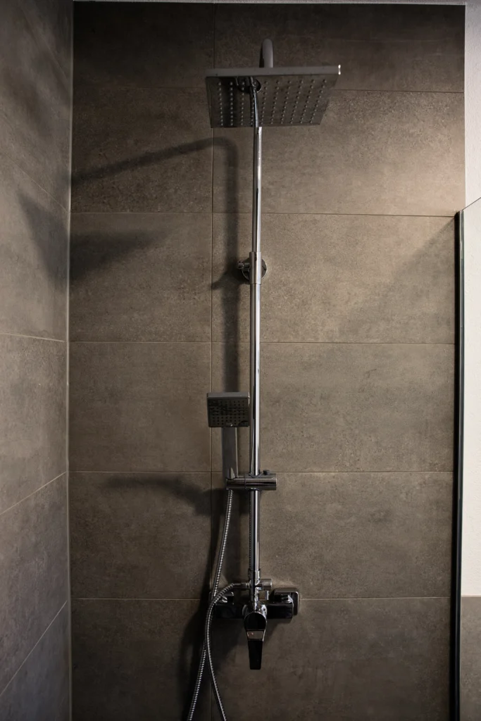 Moderne Dusche mit grauen Wandfliesen und verchromter Armatur