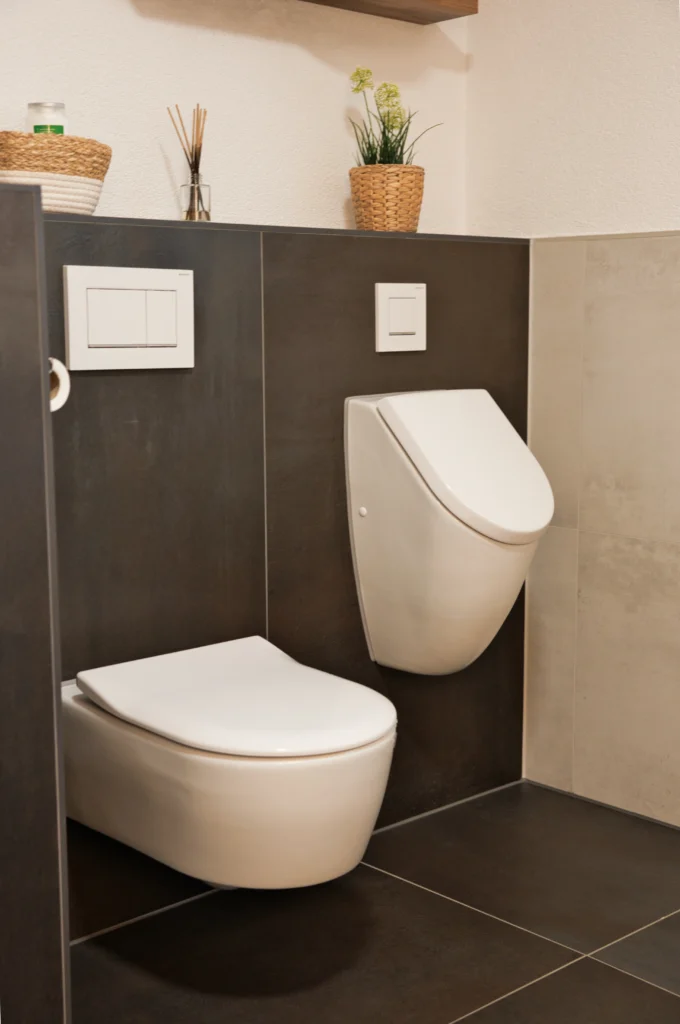 WC- und Bidetbereich mit dunkler Feinsteinzeugfliese in Metalloptik als Vorwandverkleidung und integrierter Ablage