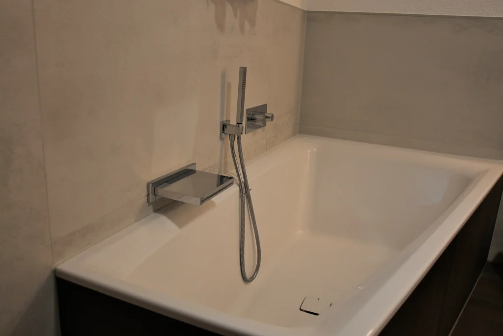 Detailansicht Badewanne mit Wandfliese Monocibec Blade Pure und verchromten Armaturen im modernen Bad