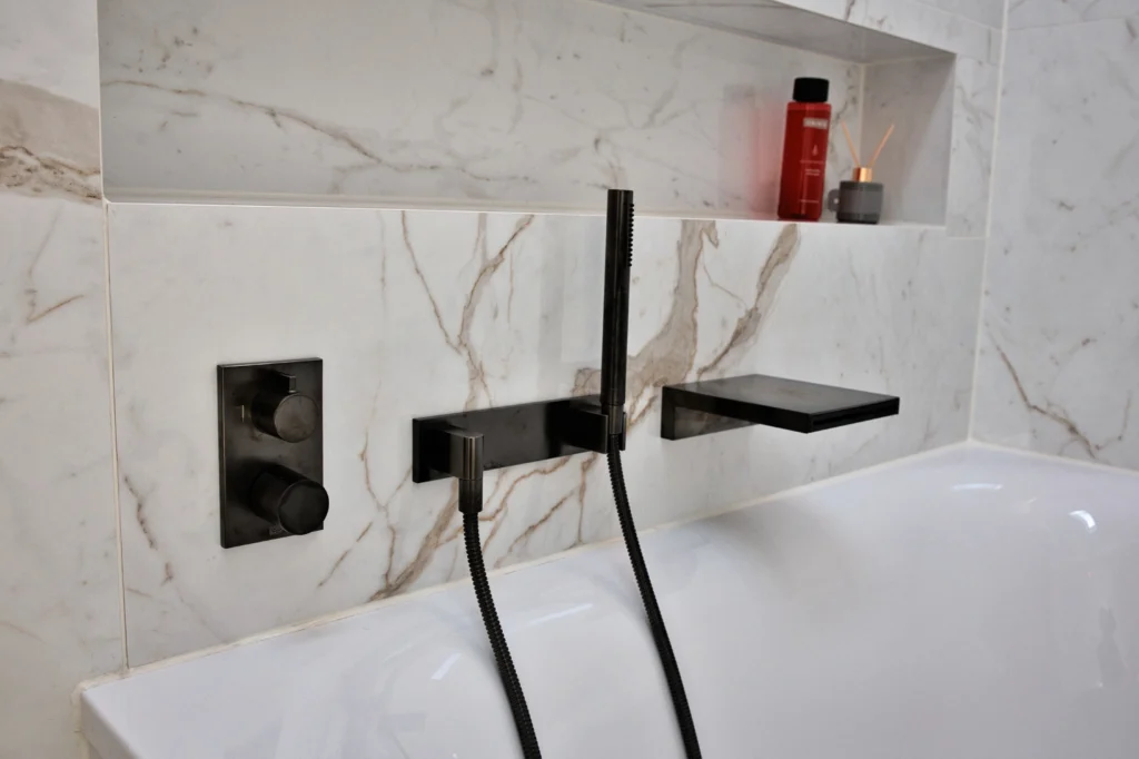 Badewannenarmaturen von Herzbach in Dark Platinum matt auf Wandfliesen in Marmoroptik mit integrierter Nische