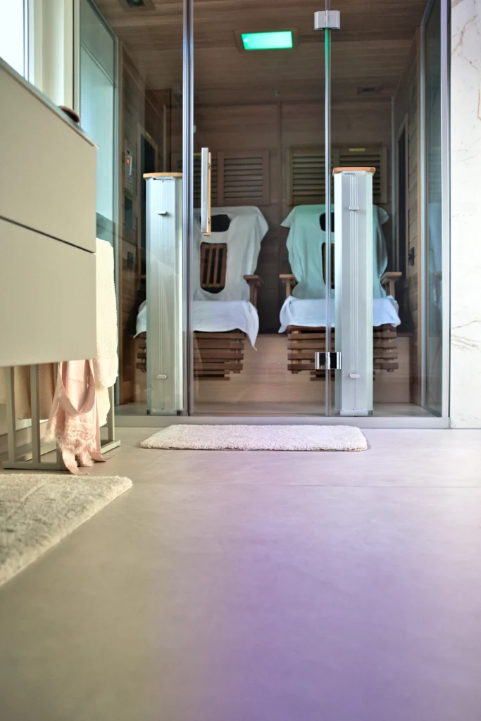 Großformatige Bodenfliese Atlas Concorde Prism in Betonoptik im Badezimmer vor Glasfront zur Sauna