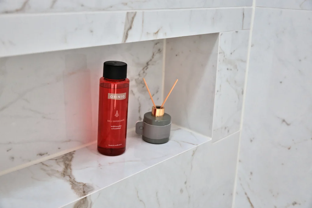 Detailaufnahme einer integrierten Wandnische in Marmoroptik mit dekorativen Accessoires im luxuriösen Badezimmer